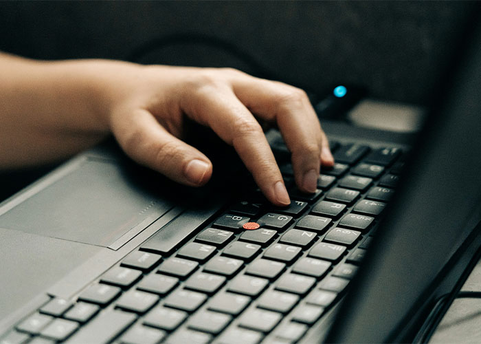 Someone typing on a laptop online