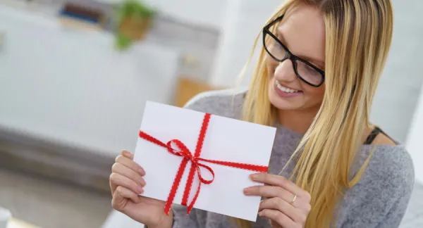 Woman holding a white envelope wrapped in a red ribbon