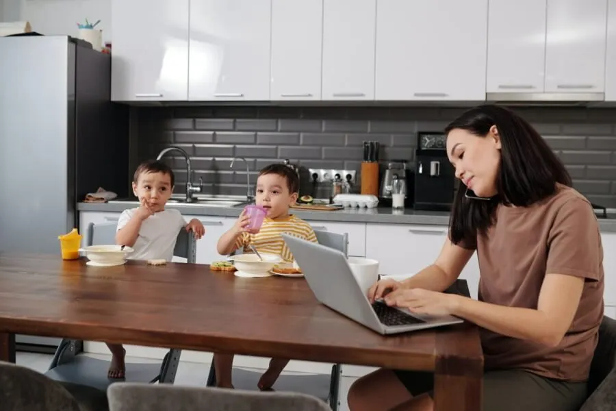 Mother on the phone with two small children sat at a table