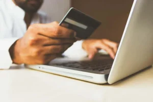 Man with credit card inputting details onto laptop