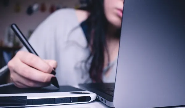 Brown-haired woman on a laptop making notes on no-obligation debt advice