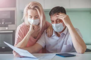 two people sitting with face masks reading a document