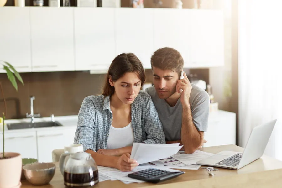 Couple on the phone looking at laptop screen