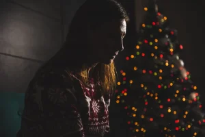 girl sitting next to Christmas tree worrying about debt