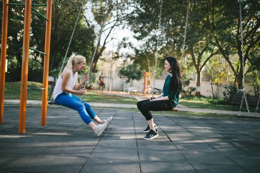 time to talk - two woman sat on swings talking