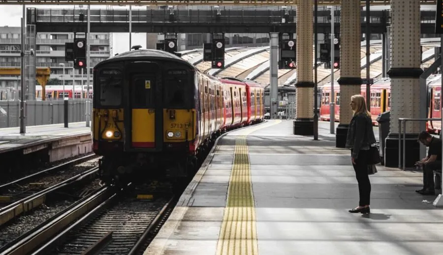 travel disruption - woman waiting on a platform with a train approaching