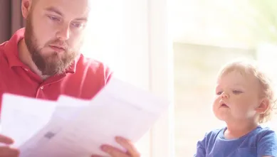Man looking at default notices with his child sat next to him