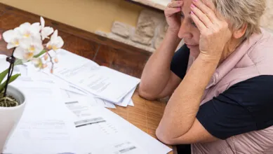 Older woman looking worried at bills in front of her on the table