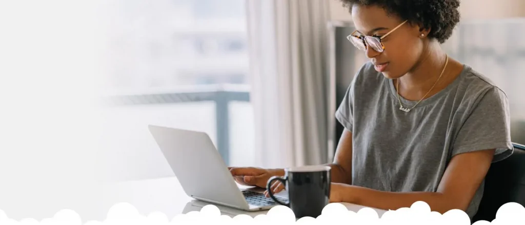 Woman with glasses sat at the table looking at her laptop