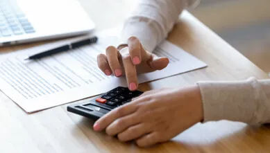 Woman with pink nail polish on typing onto a calculator