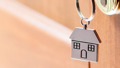 Metal house keychain handing off a key in the door handle