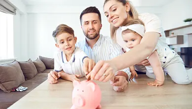 Family placing coins into a pink money bank