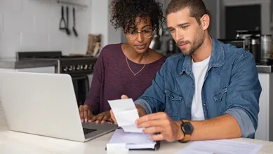 Couple looking at receipts in front of a laptop