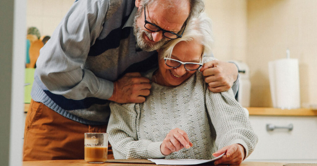 smiling elderly couple looking at their finances