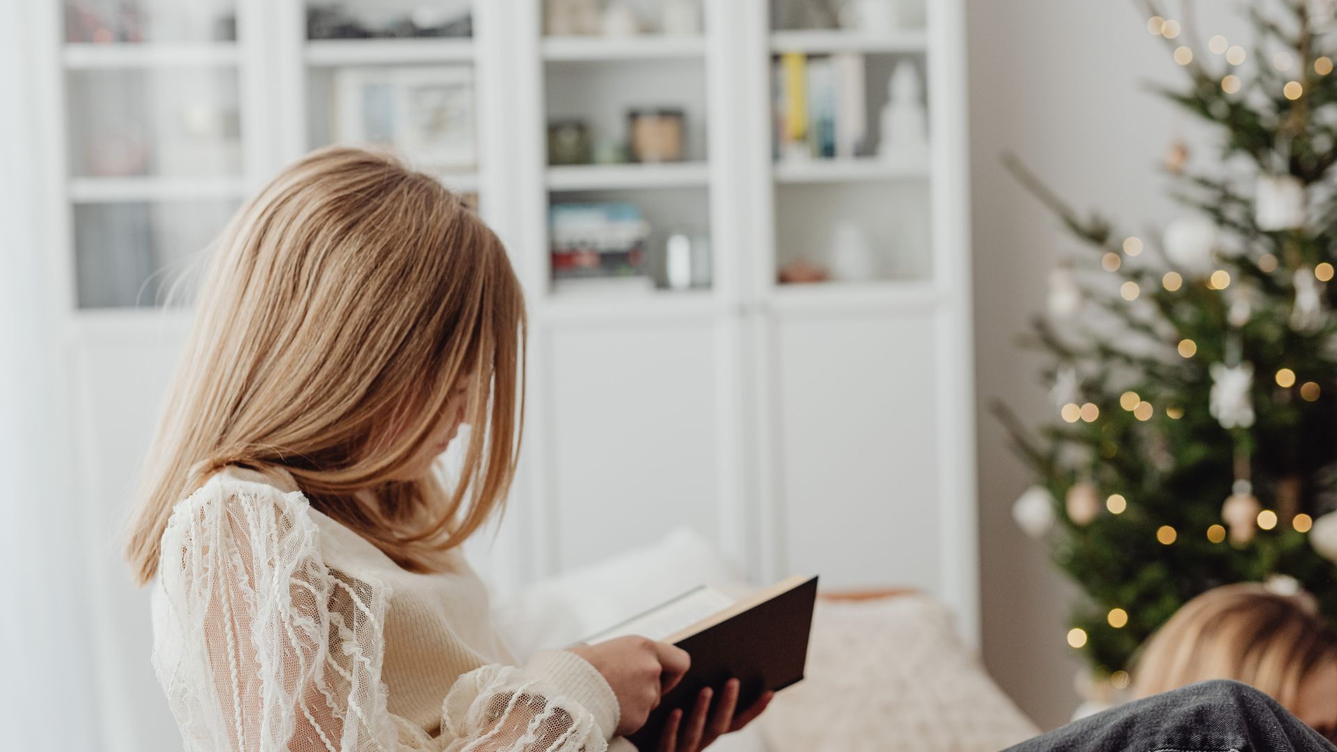 woman sat reading next to Christmas tree