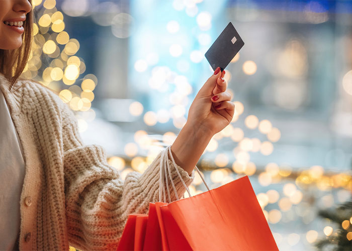 a happy woman shopping holding a card in her hand getting christmas deals 2025