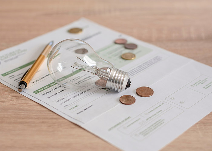 an energy bill with coins, a pencil and a lightbulb on it