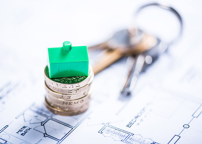a stack of coins on top of plans for a house