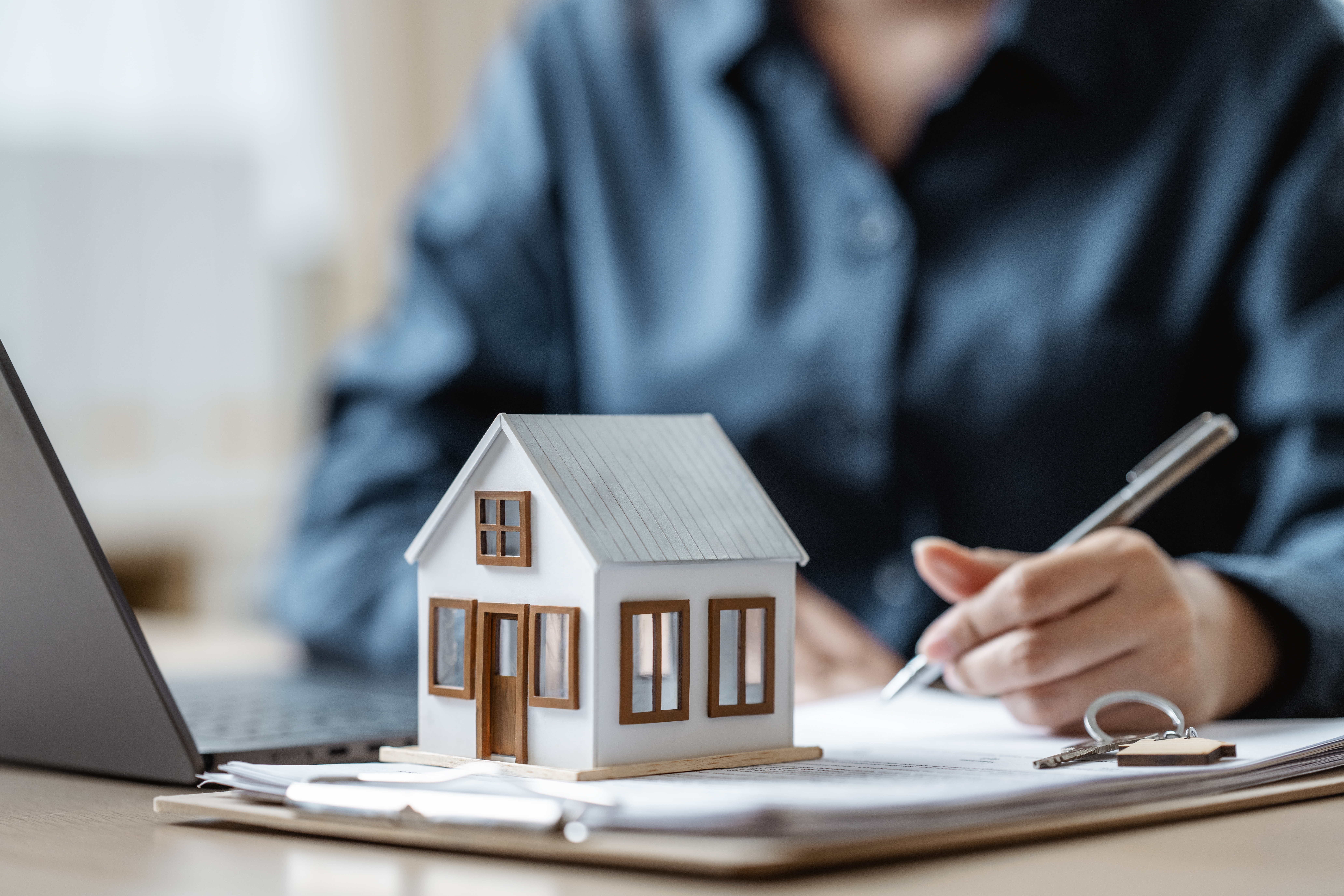 A person sitting at a desk with a laptop and a small model of a house.